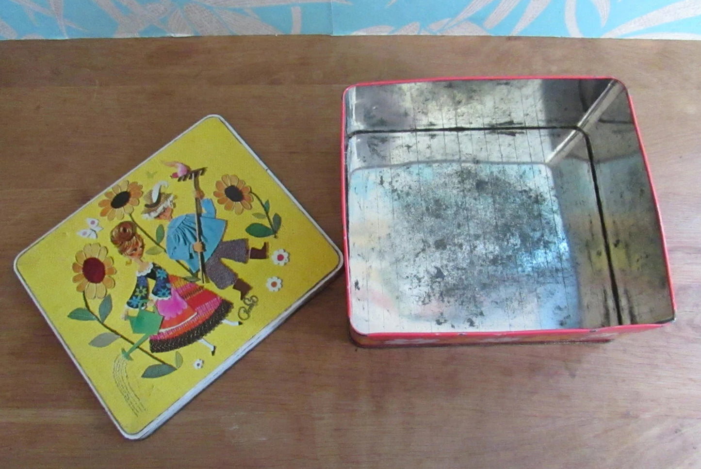 1960s/70s yellow & orange floral patterned tin, kitsch couple on lid watering sunflowers