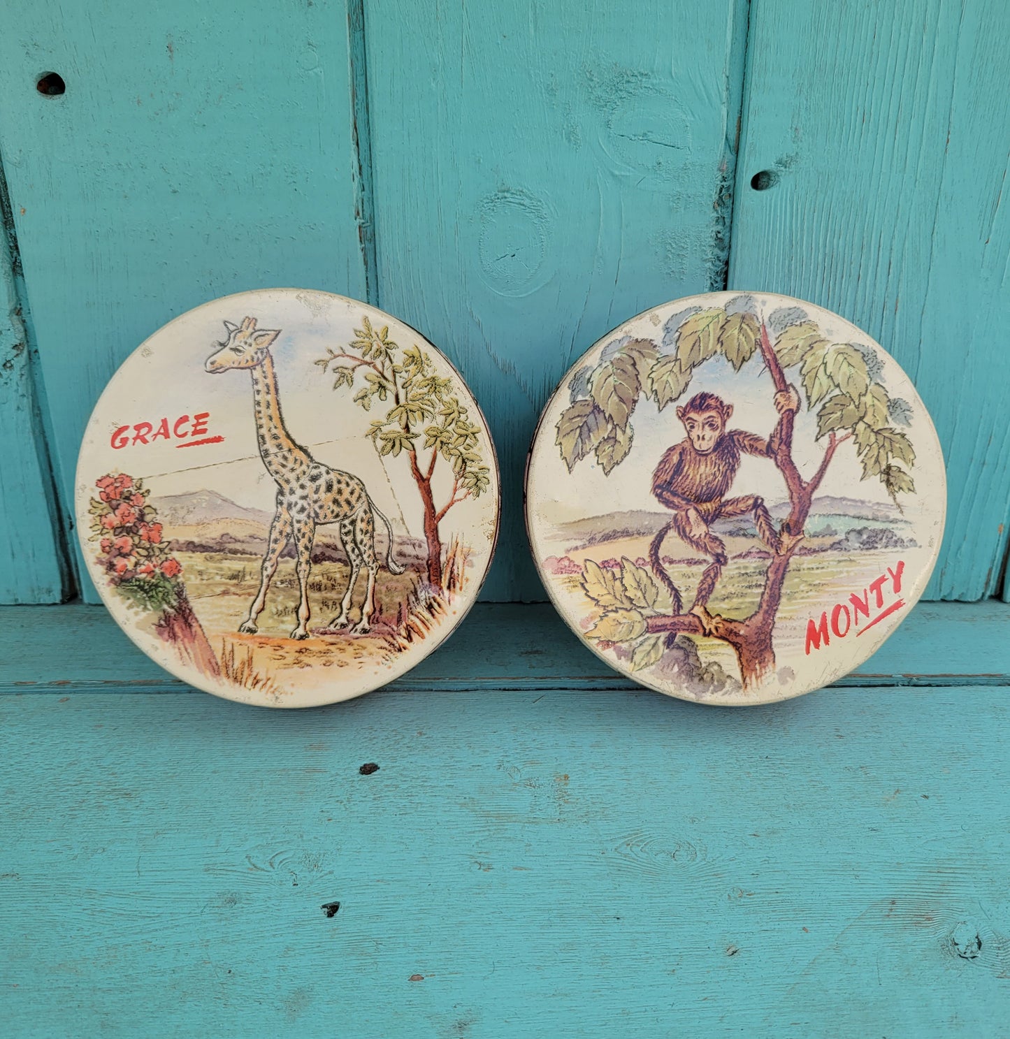 Two 1950s Huntley & Palmer's round mini biscuit tins, Grace the giraffe, and Monty the monkey
