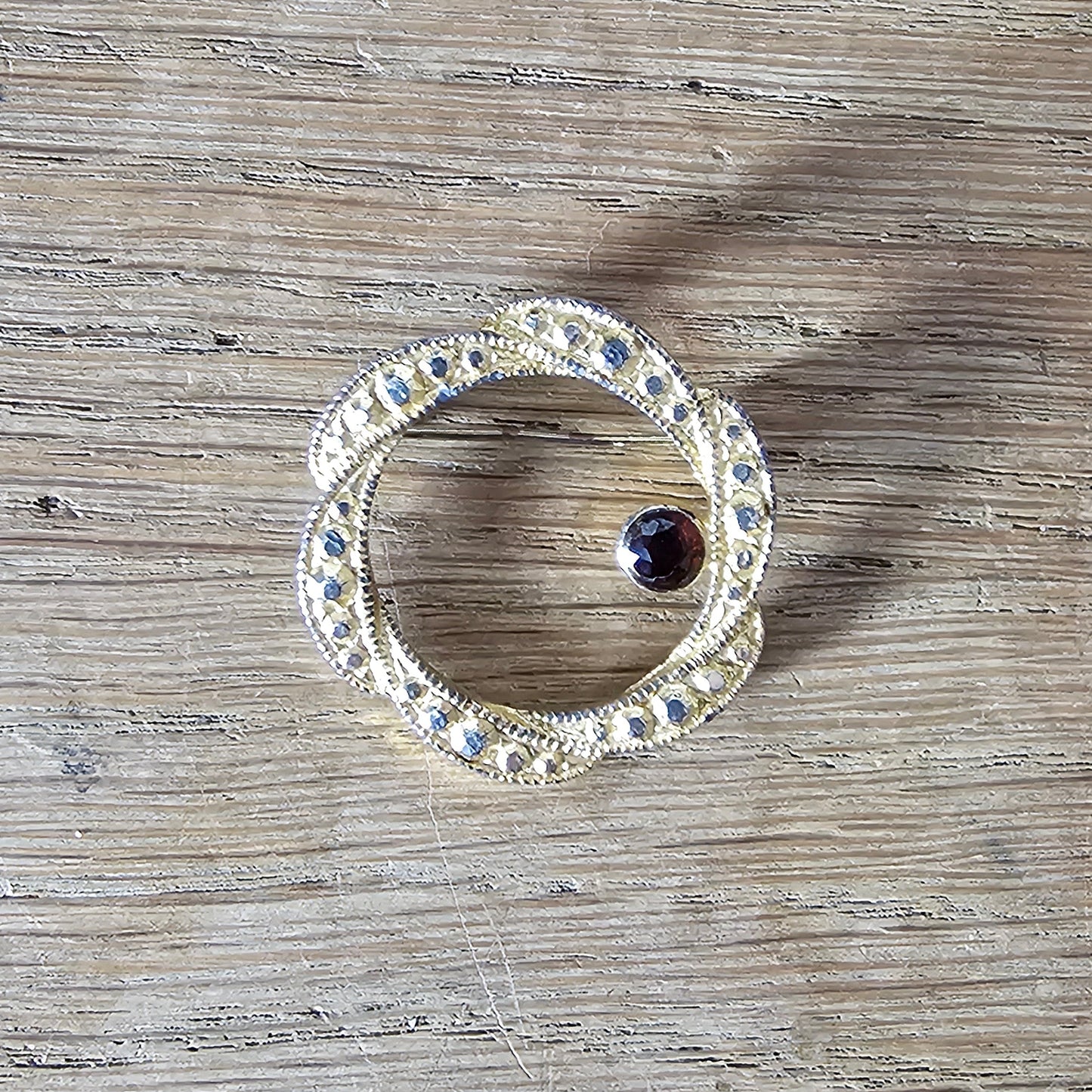 1980s gold-tone faux marcasite circle brooch with garnet rhinestone