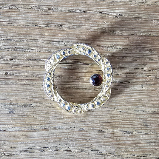 1980s gold-tone faux marcasite circle brooch with garnet rhinestone