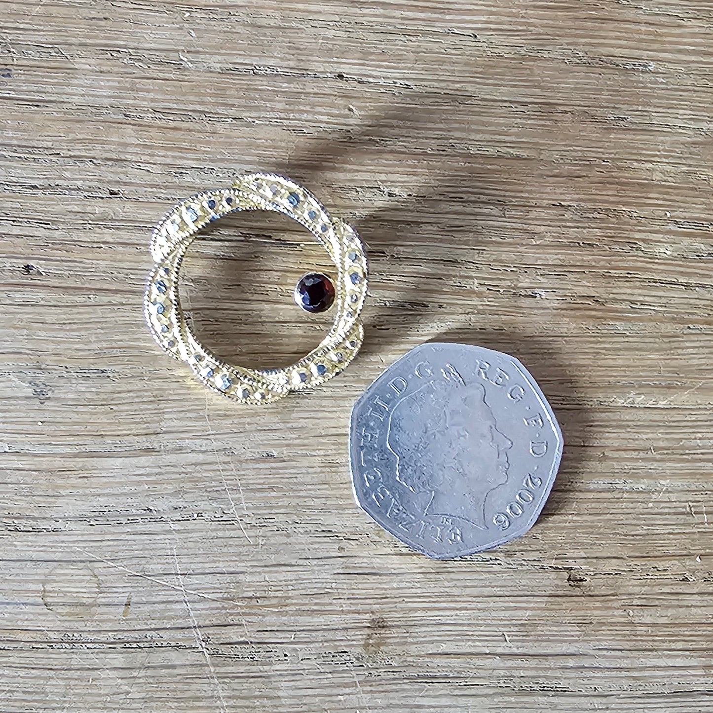 1980s gold-tone faux marcasite circle brooch with garnet rhinestone