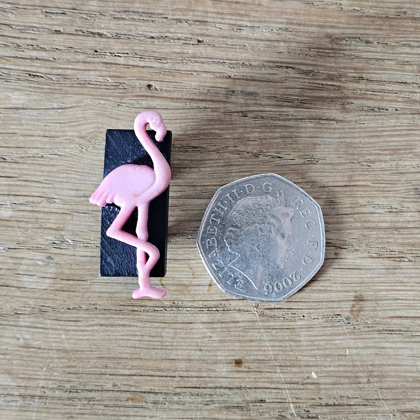 Home-made brooch using pink plastic flamingo on rectangular wooden bead