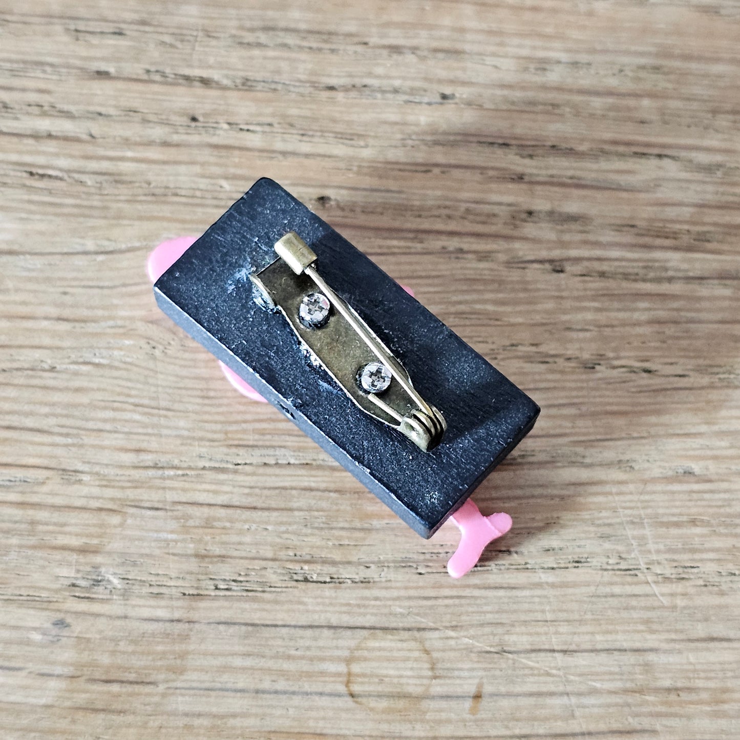 Home-made brooch using pink plastic flamingo on rectangular wooden bead