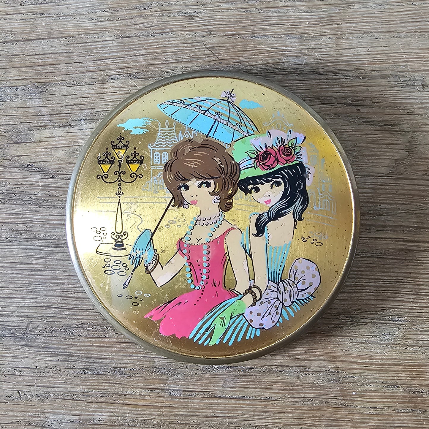 1960s gold-tone powder compact with mod fashion illustration design