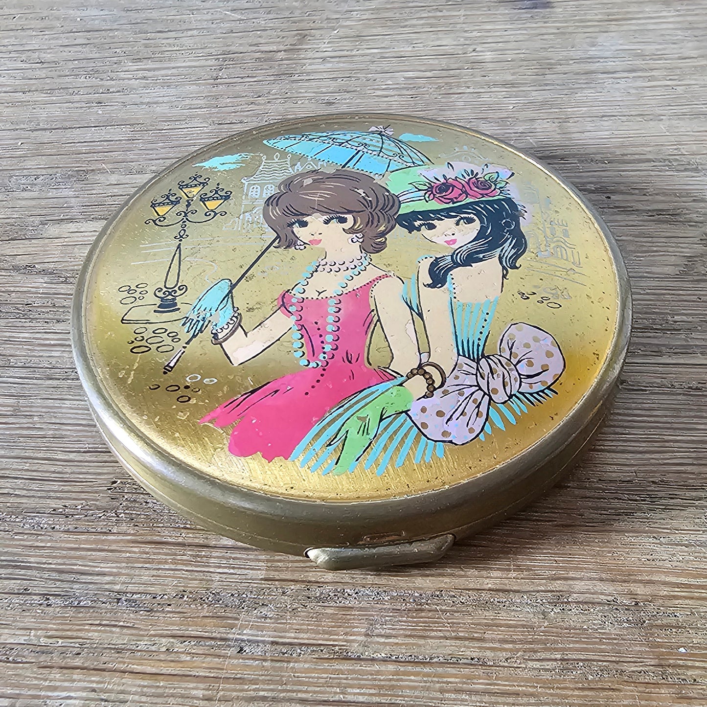 1960s gold-tone powder compact with mod fashion illustration design
