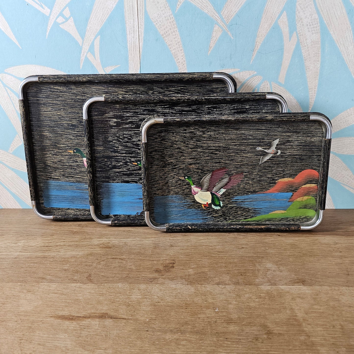 Set of three 1950s hand-painted black serving trays with flying duck detail