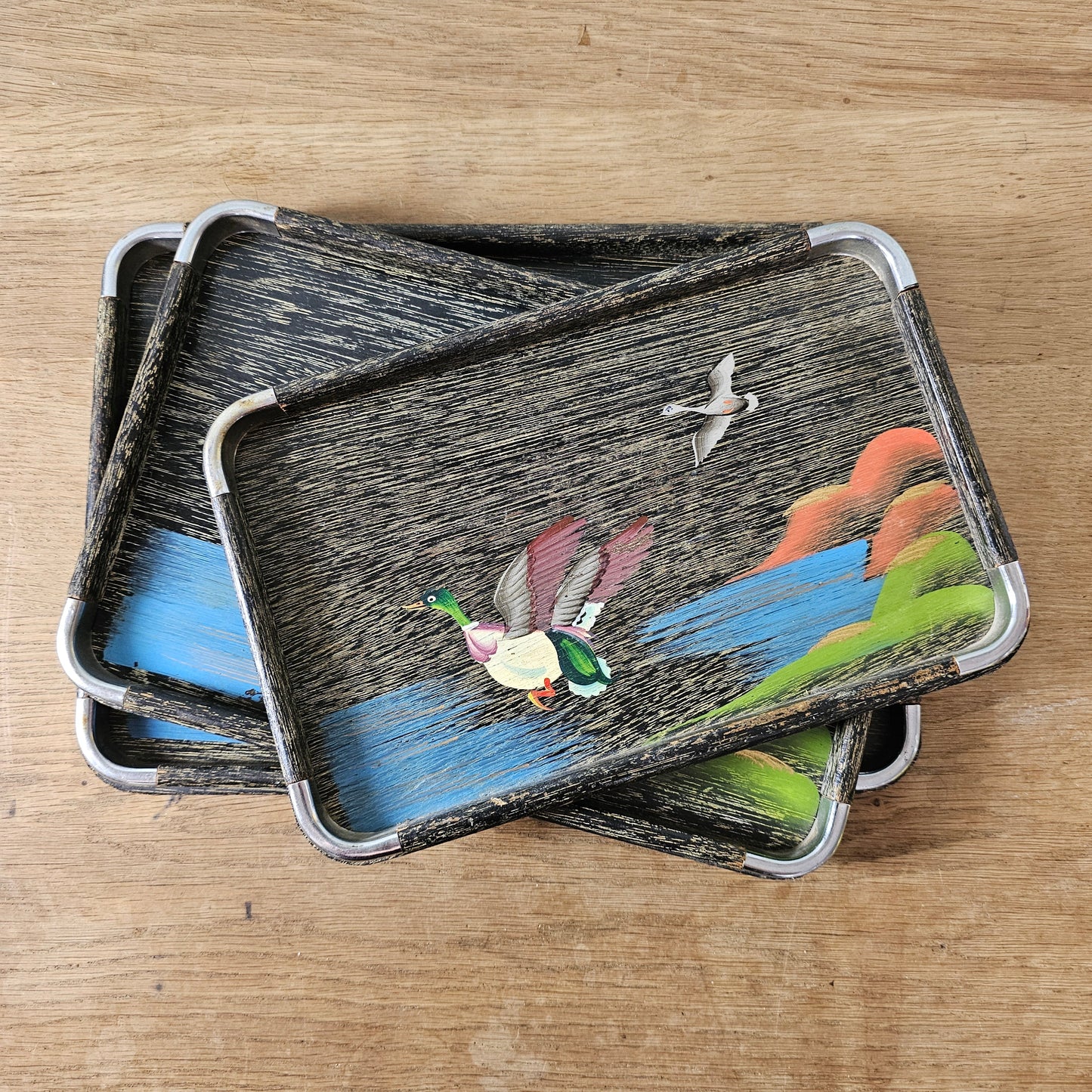 Set of three 1950s hand-painted black serving trays with flying duck detail