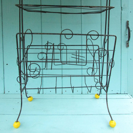 Mid-century metal atomic music note magazine rack with woven handle and ball feet detail