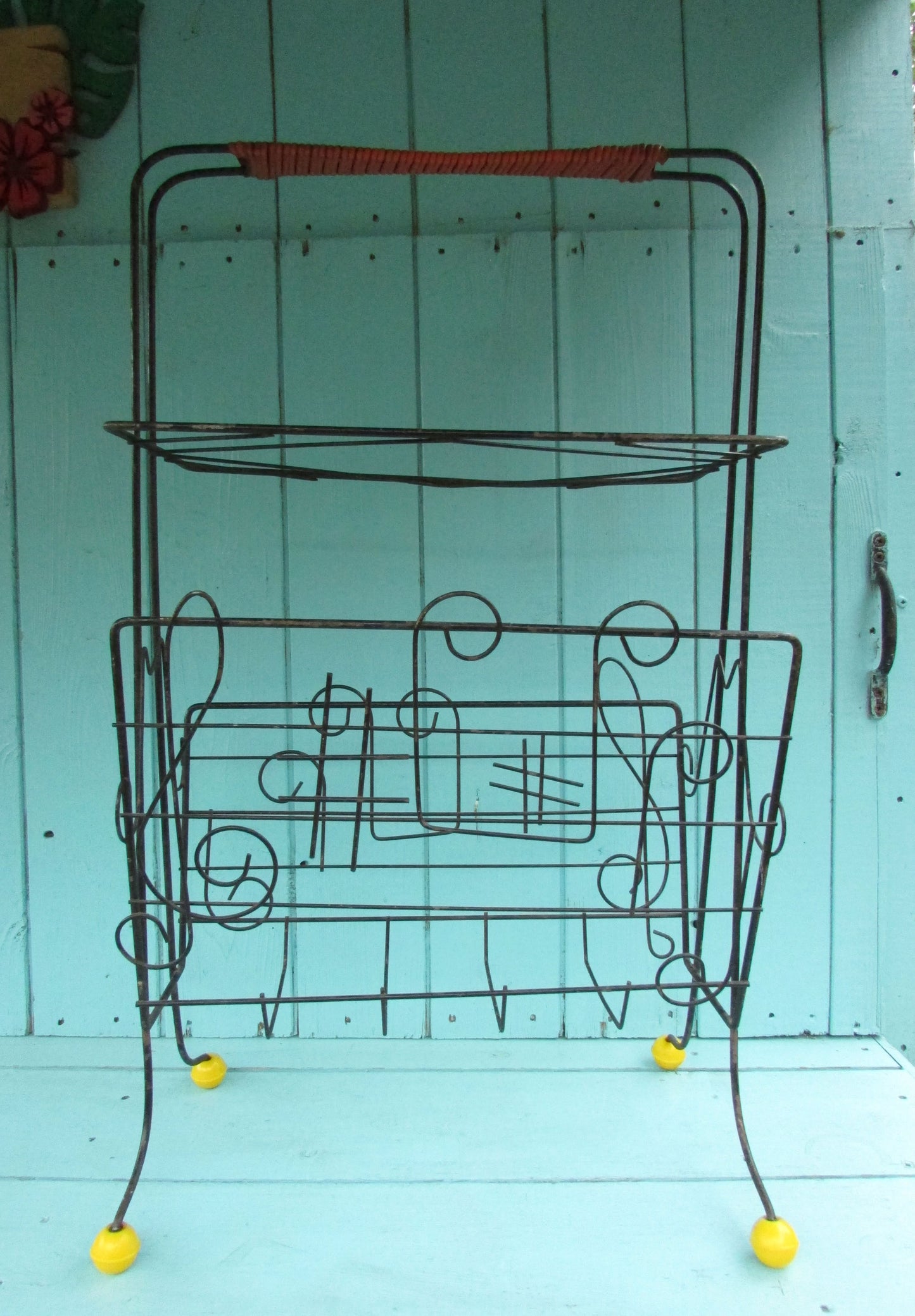 Mid-century metal atomic music note magazine rack with woven handle and ball feet detail