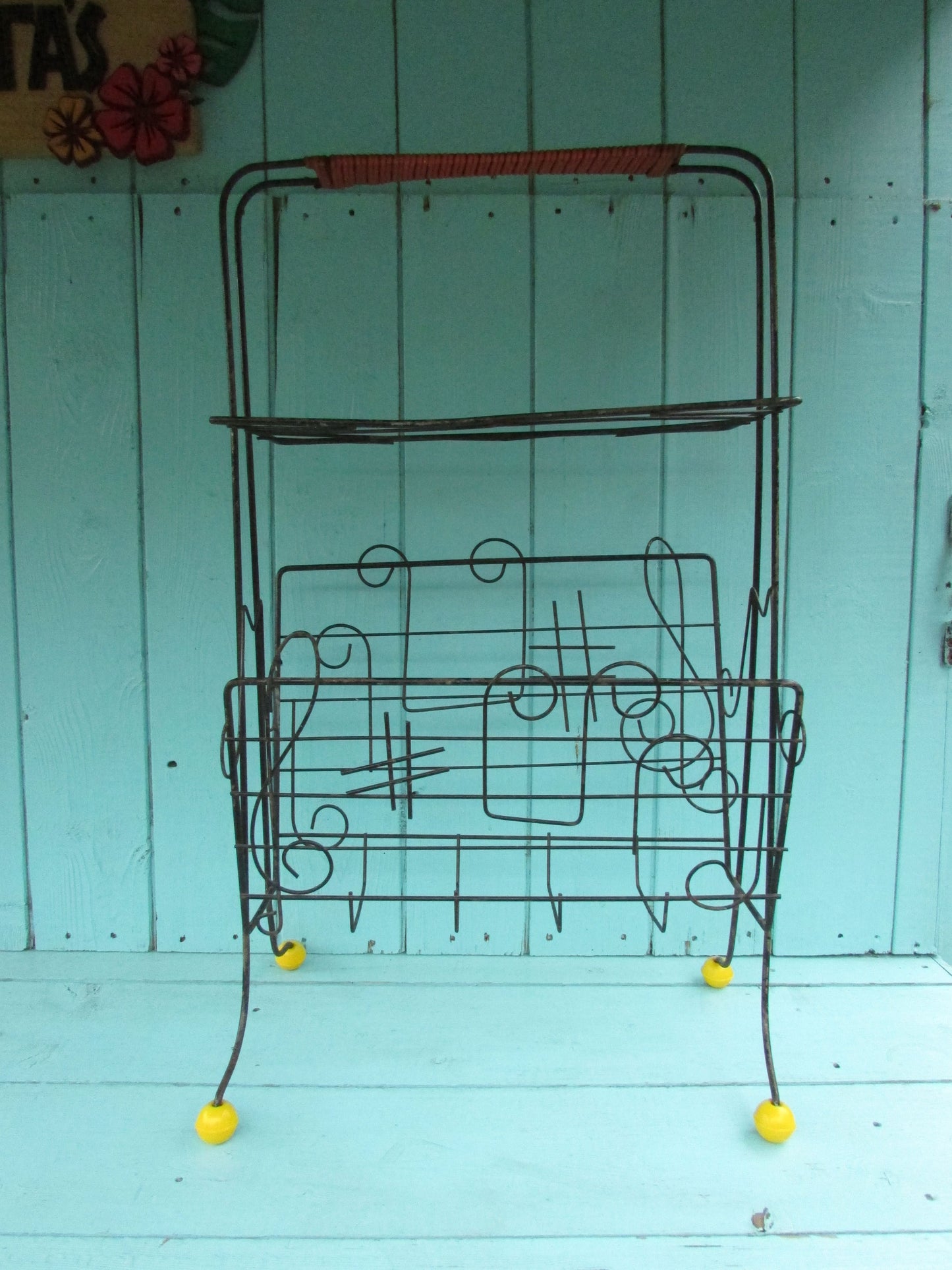 Mid-century metal atomic music note magazine rack with woven handle and ball feet detail