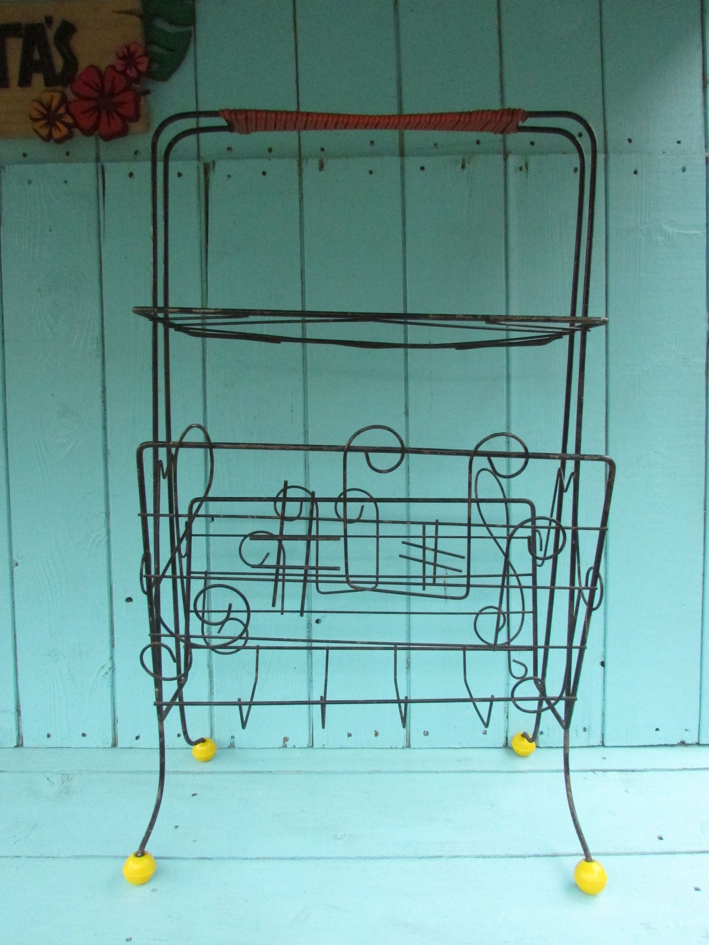 Mid-century metal atomic music note magazine rack with woven handle and ball feet detail