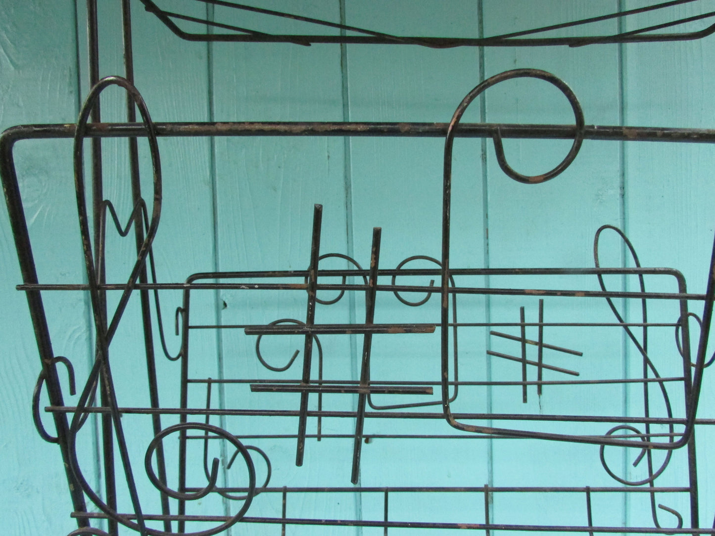 Mid-century metal atomic music note magazine rack with woven handle and ball feet detail