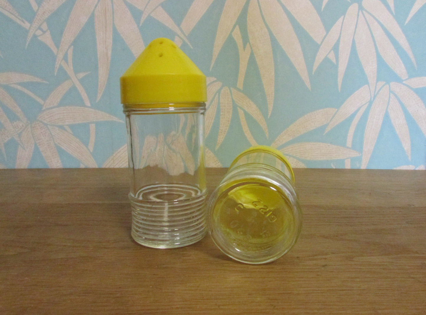 Pair of 1960s glass sugar pourers with yellow plastic lids