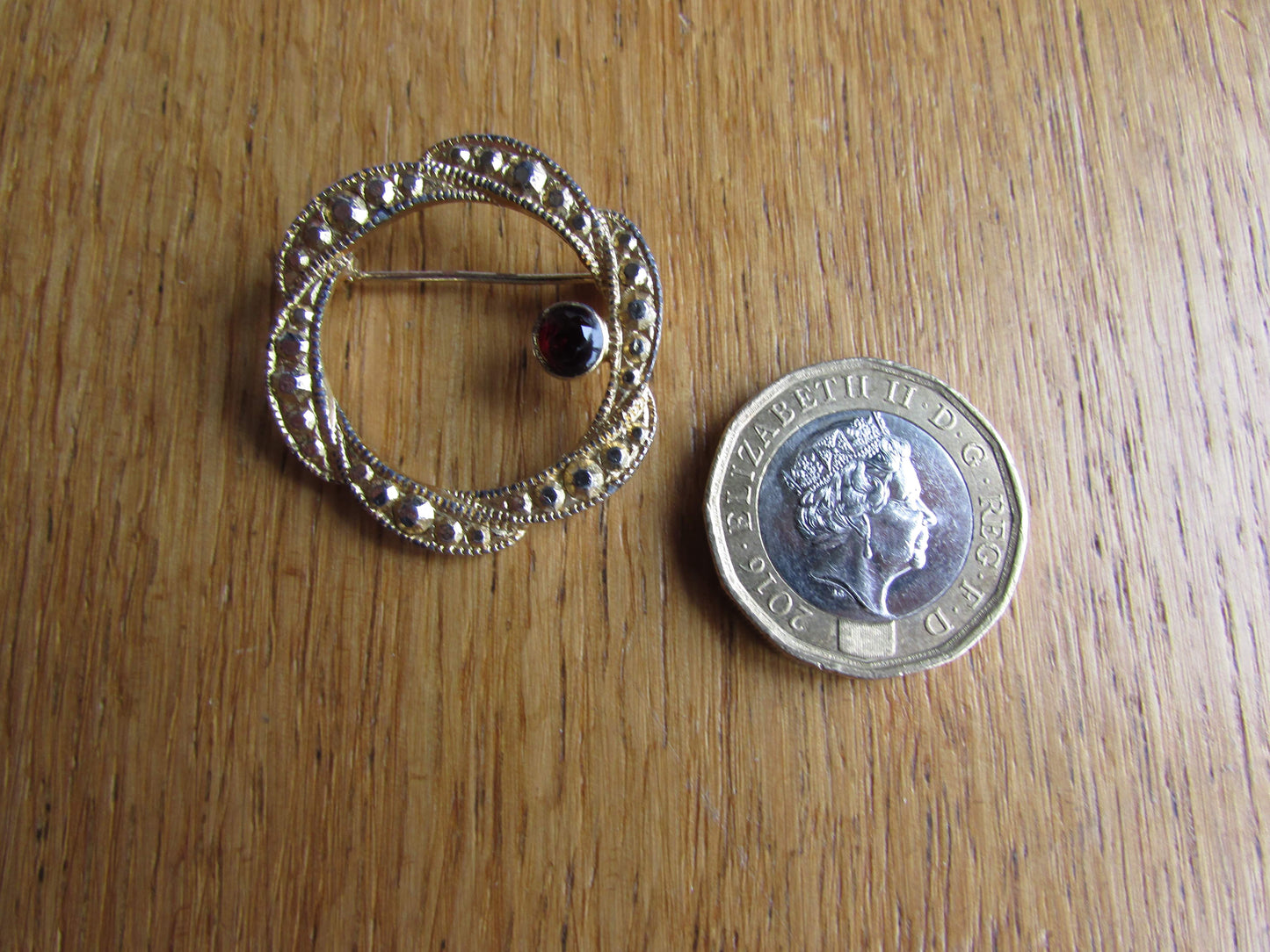 Vintage gold-tone ribbon swirl circlet brooch with garnet red diamanté detail