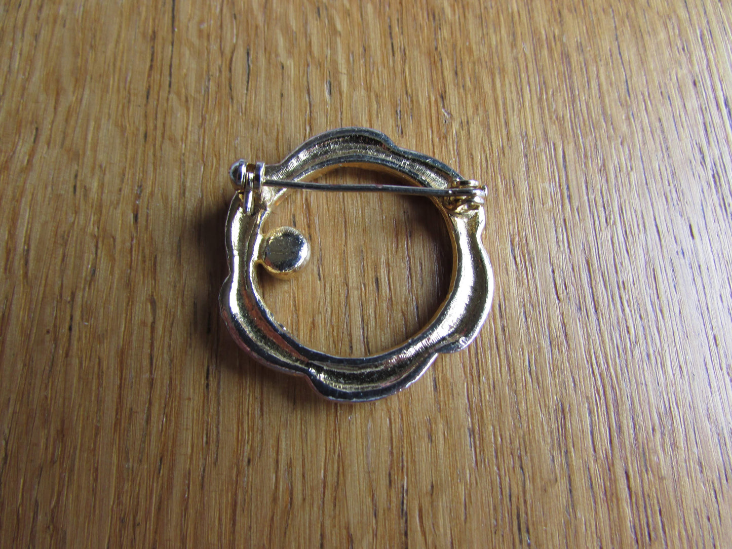 Vintage gold-tone ribbon swirl circlet brooch with garnet red diamanté detail