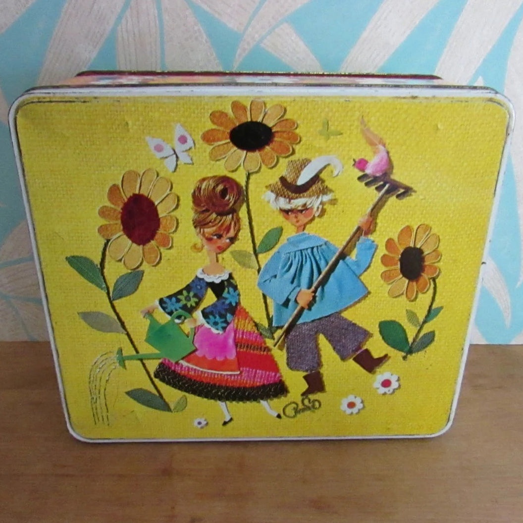1960s/70s yellow & orange floral patterned tin, kitsch couple on lid watering sunflowers