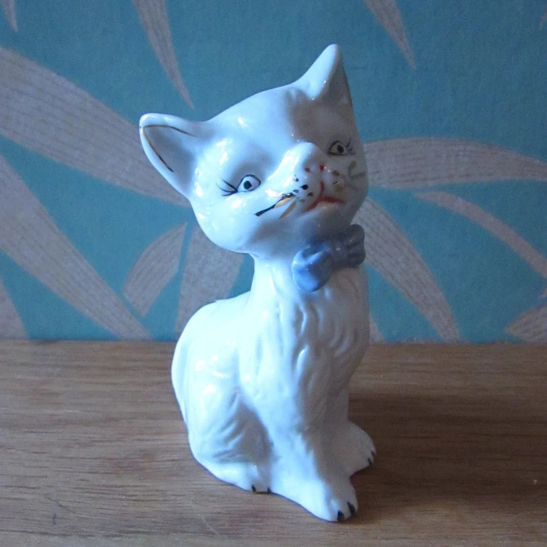 circa. 1960s kitsch white kitten ornament with blue bow
