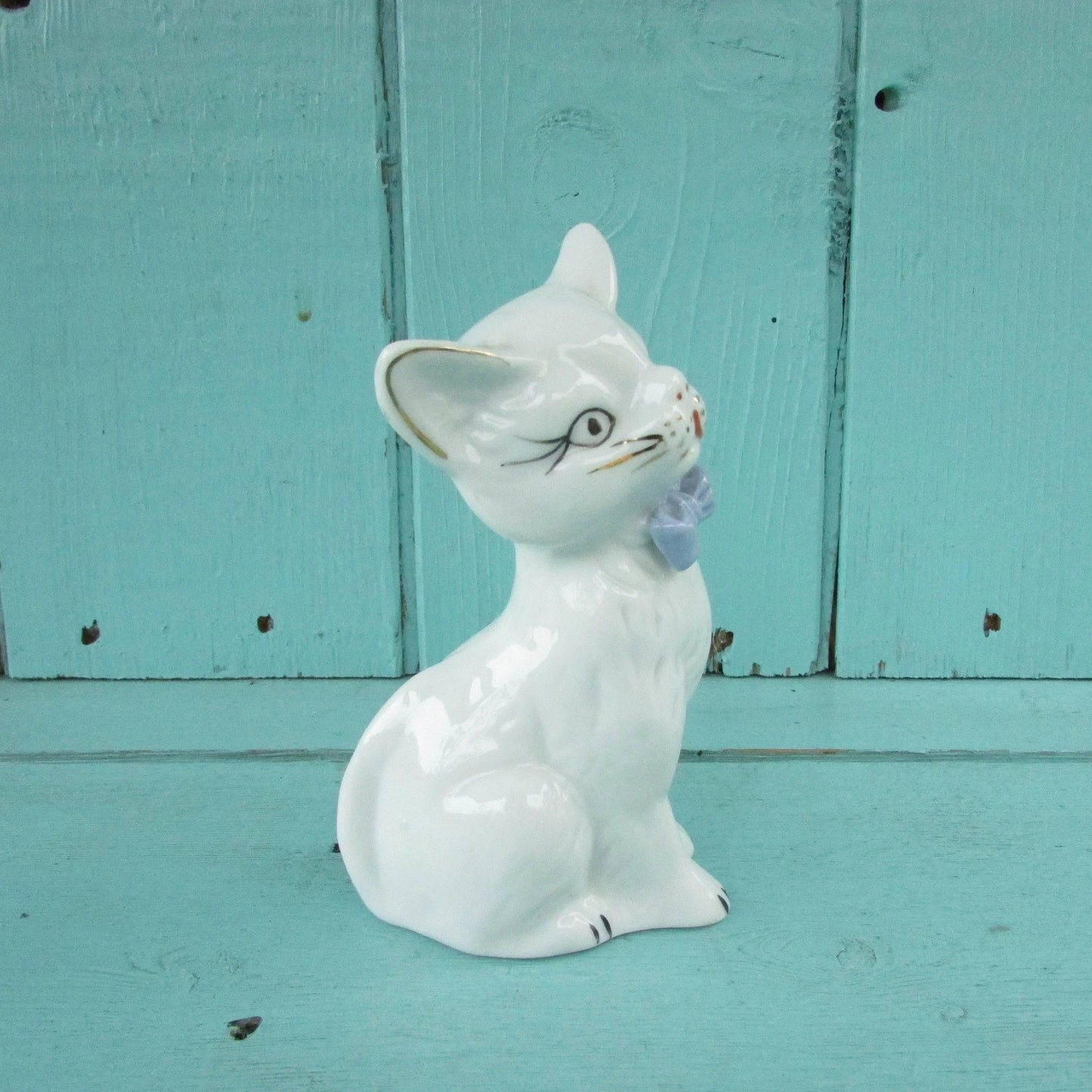 circa. 1960s kitsch white kitten ornament with blue bow detail