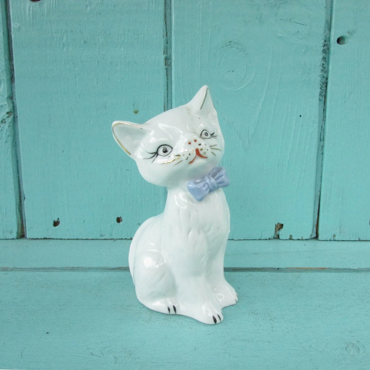 circa. 1960s kitsch white kitten ornament with blue bow detail