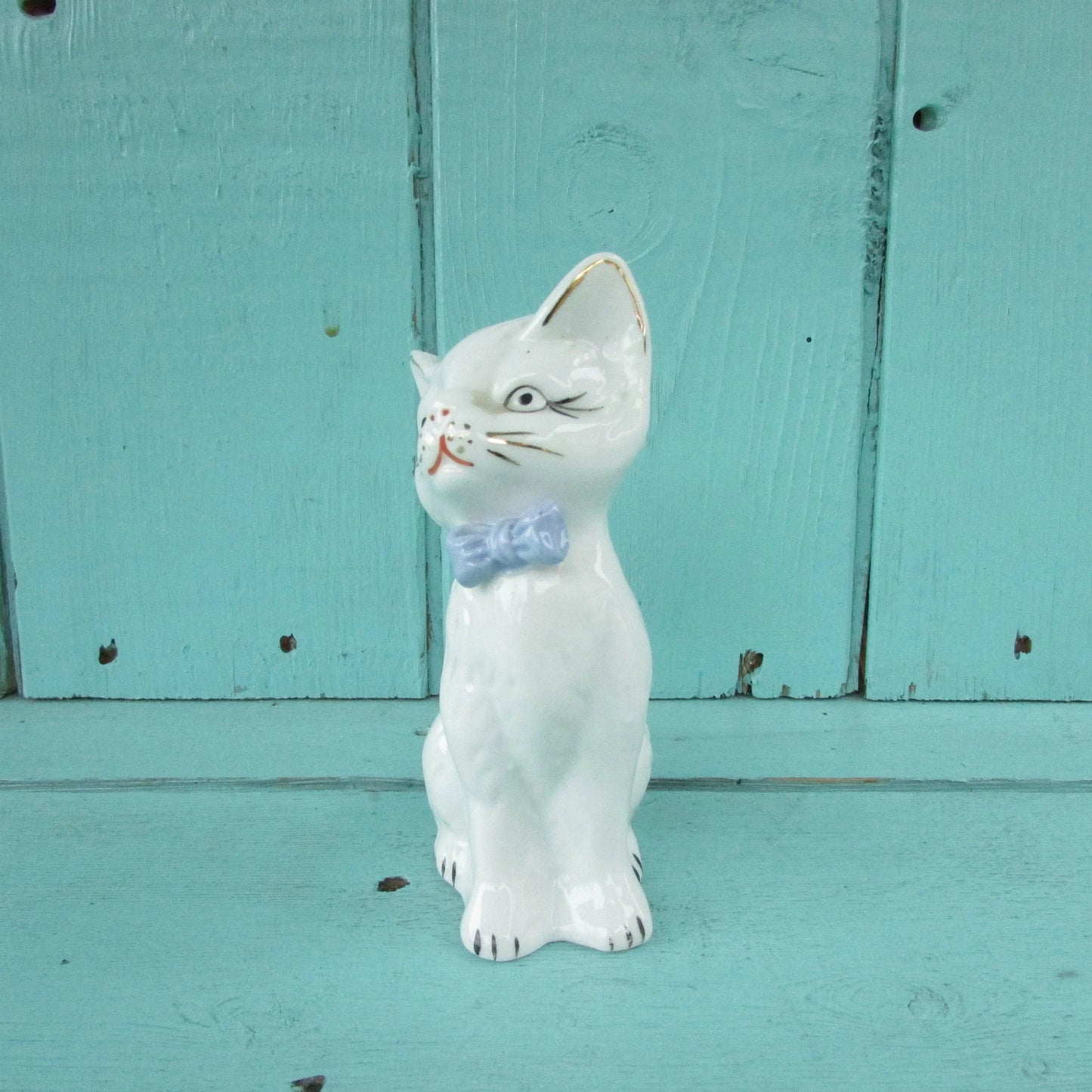 circa. 1960s kitsch white kitten ornament with blue bow detail