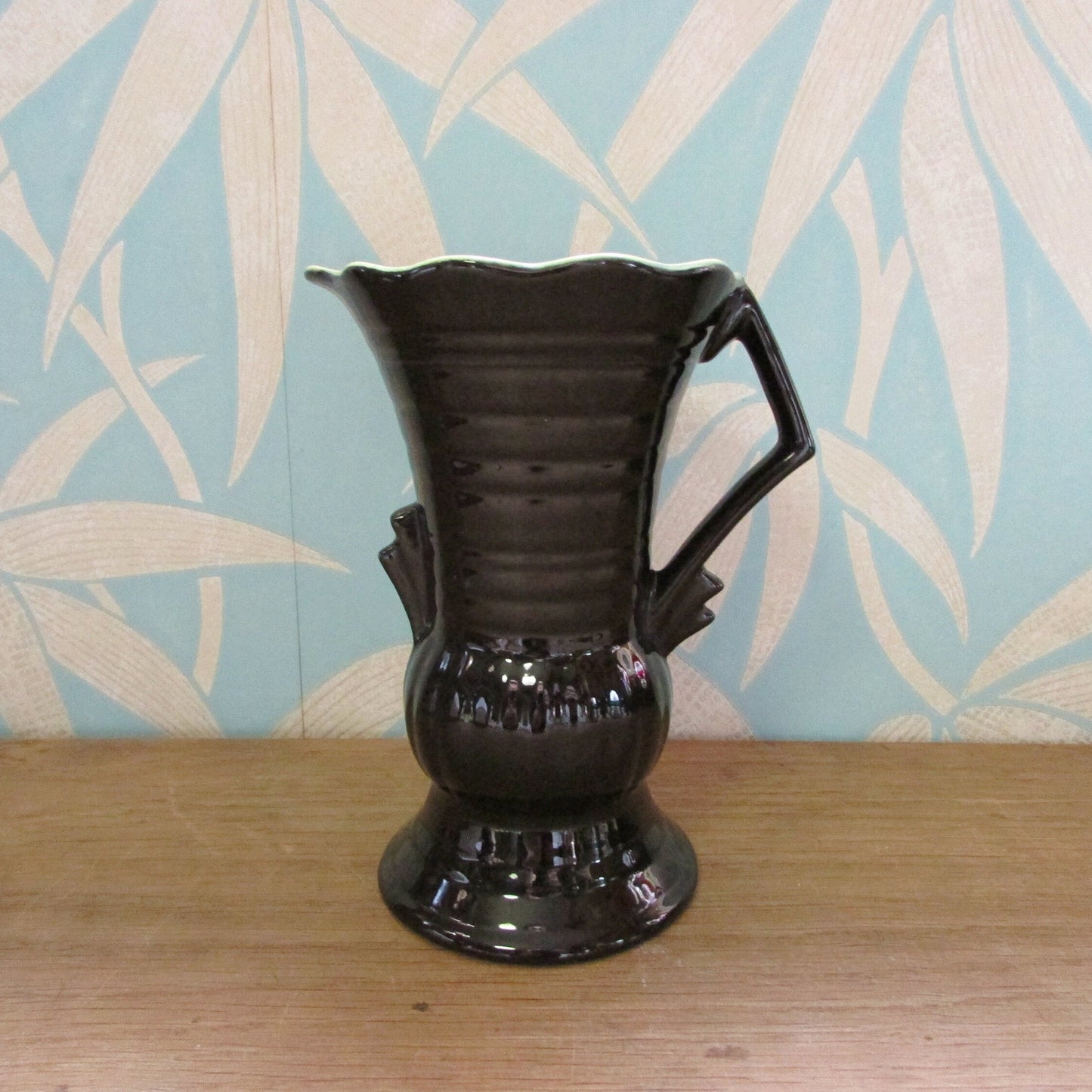 Vintage Art Deco-style black ribbed ceramic pitcher with yellow liner glaze