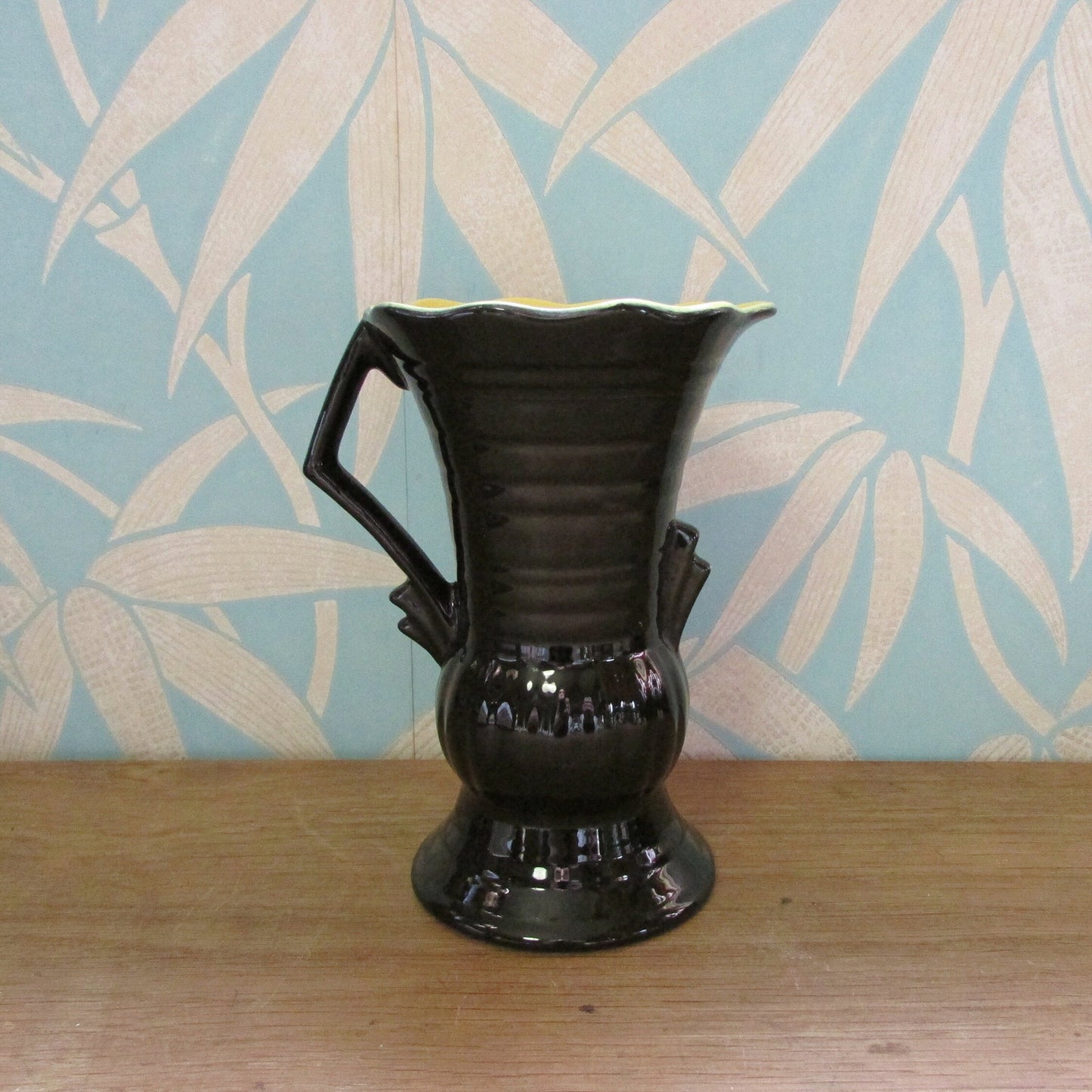Vintage Art Deco-style black ribbed ceramic pitcher with yellow liner glaze