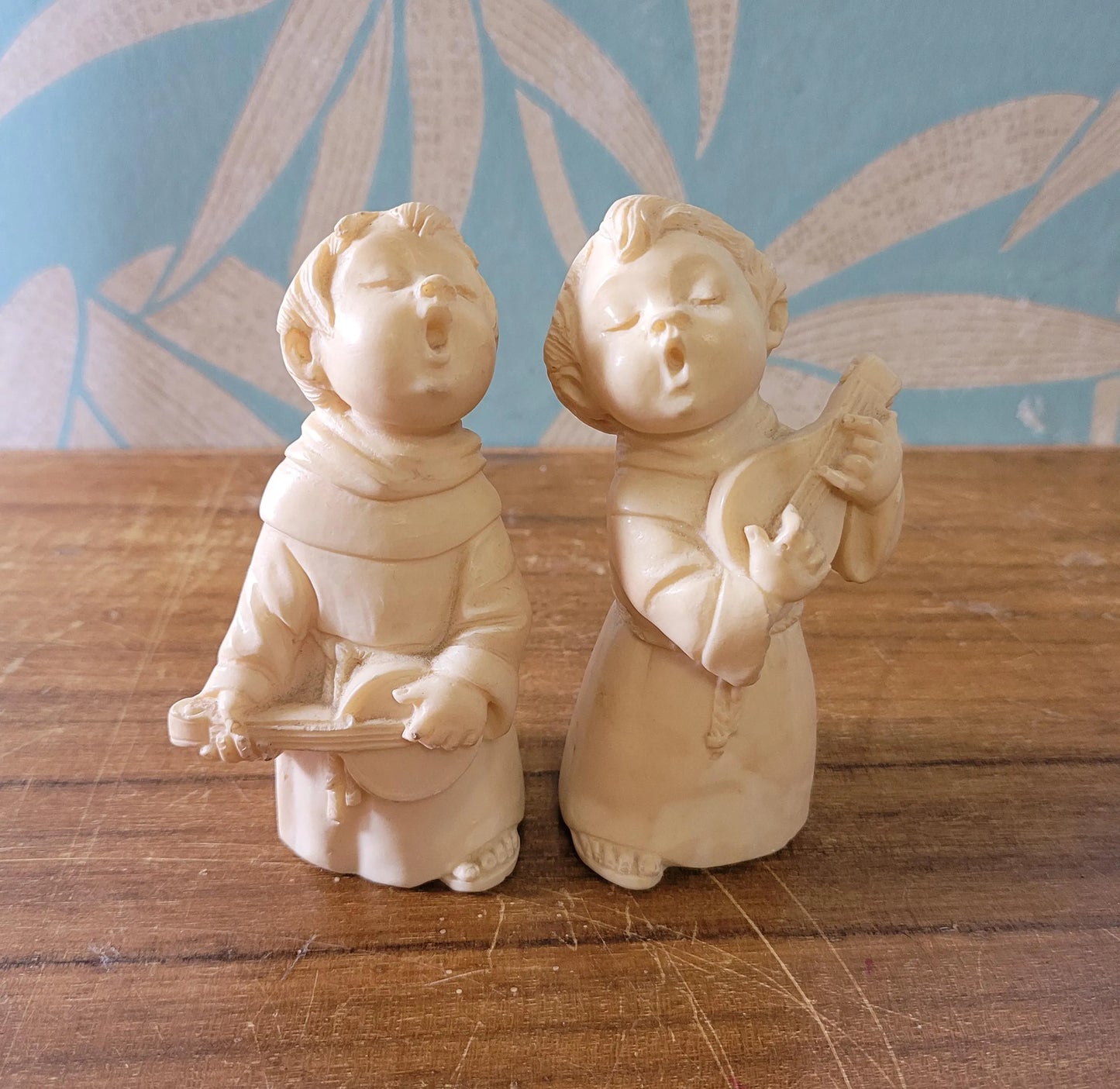 Pair of 1960s/70s ivory-coloured resin singing monk figurines, signed A. Santini