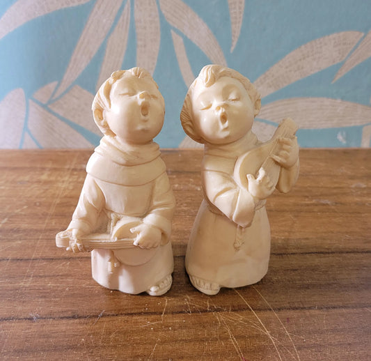 Pair of 1960s/70s ivory-coloured resin singing monk figurines, signed A. Santini