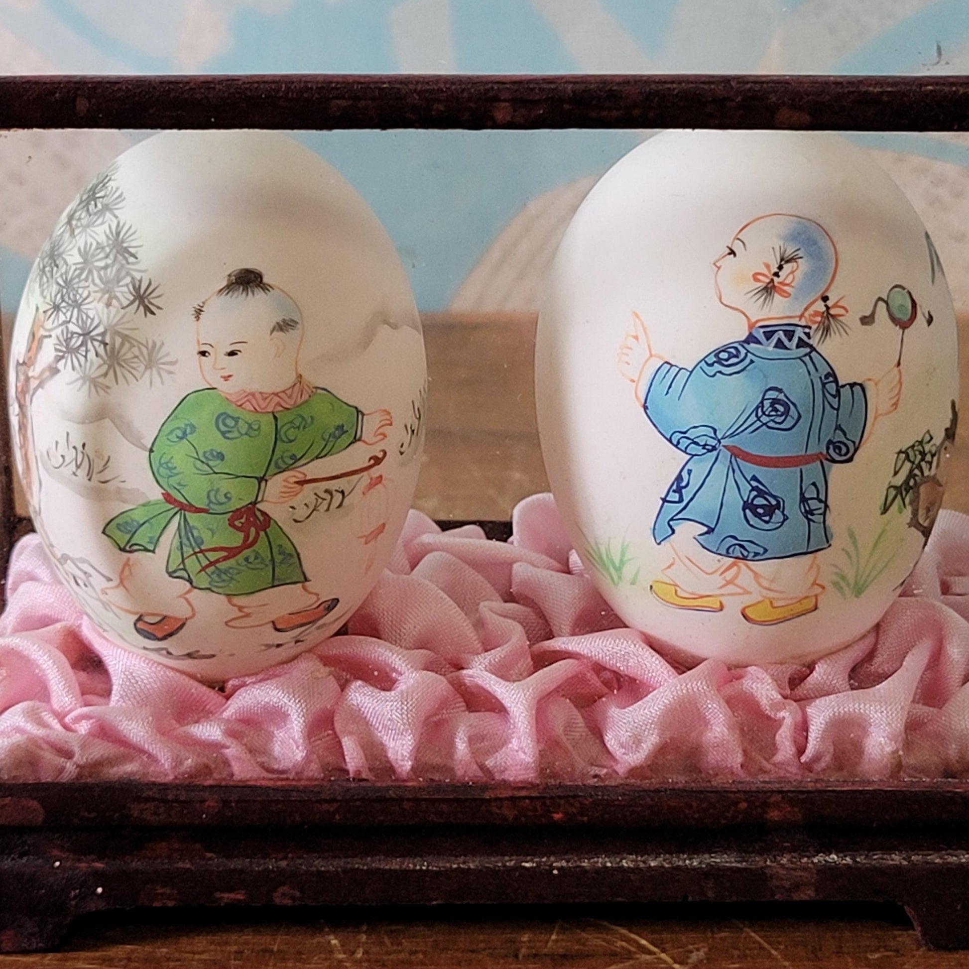 Pair of vintage Chinese hand-painted eggshells in glass display case, children playing