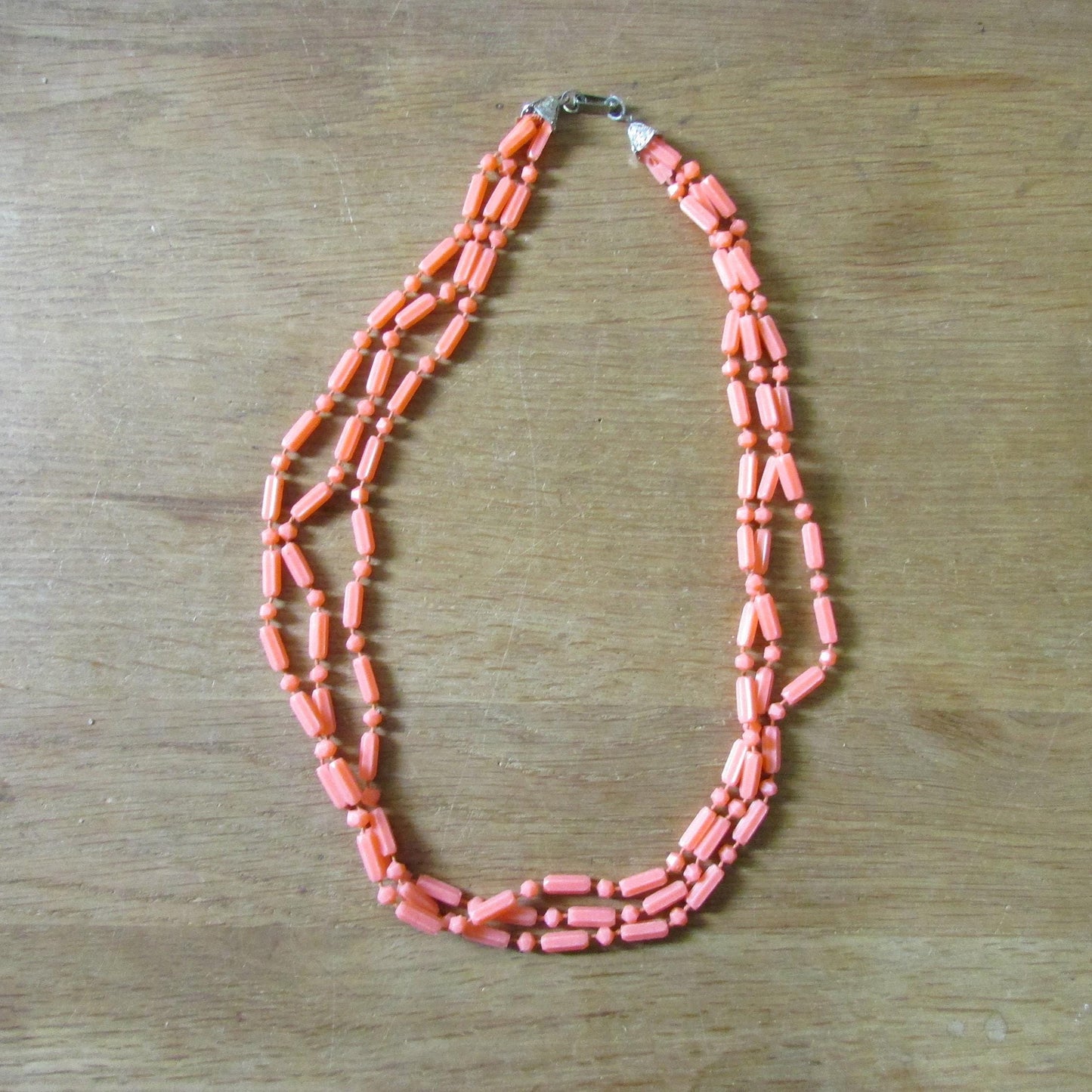 Mid-century fused plastic "dot n dash" coral bead triple strand necklace, silver-tone clasp detail