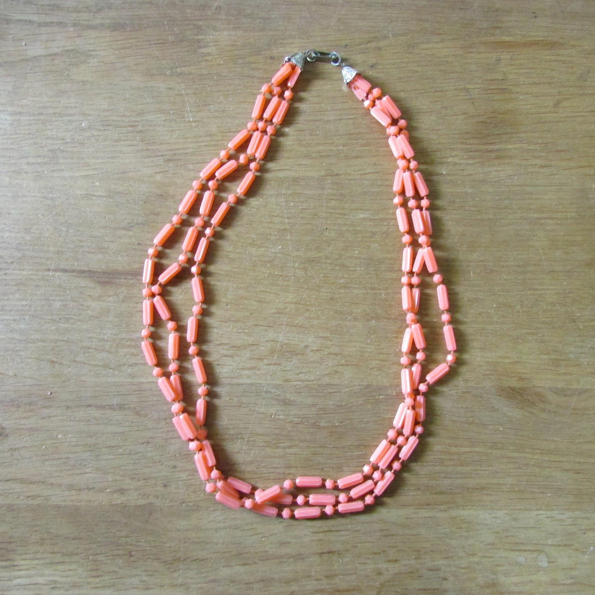 Mid-century fused plastic "dot n dash" coral bead triple strand necklace, silver-tone clasp detail