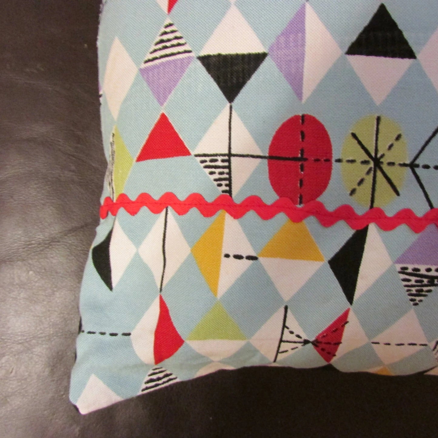 Home-made mid-century Marian Mahler atomic fabric cushion with red ric-rac, and contrast black reverse