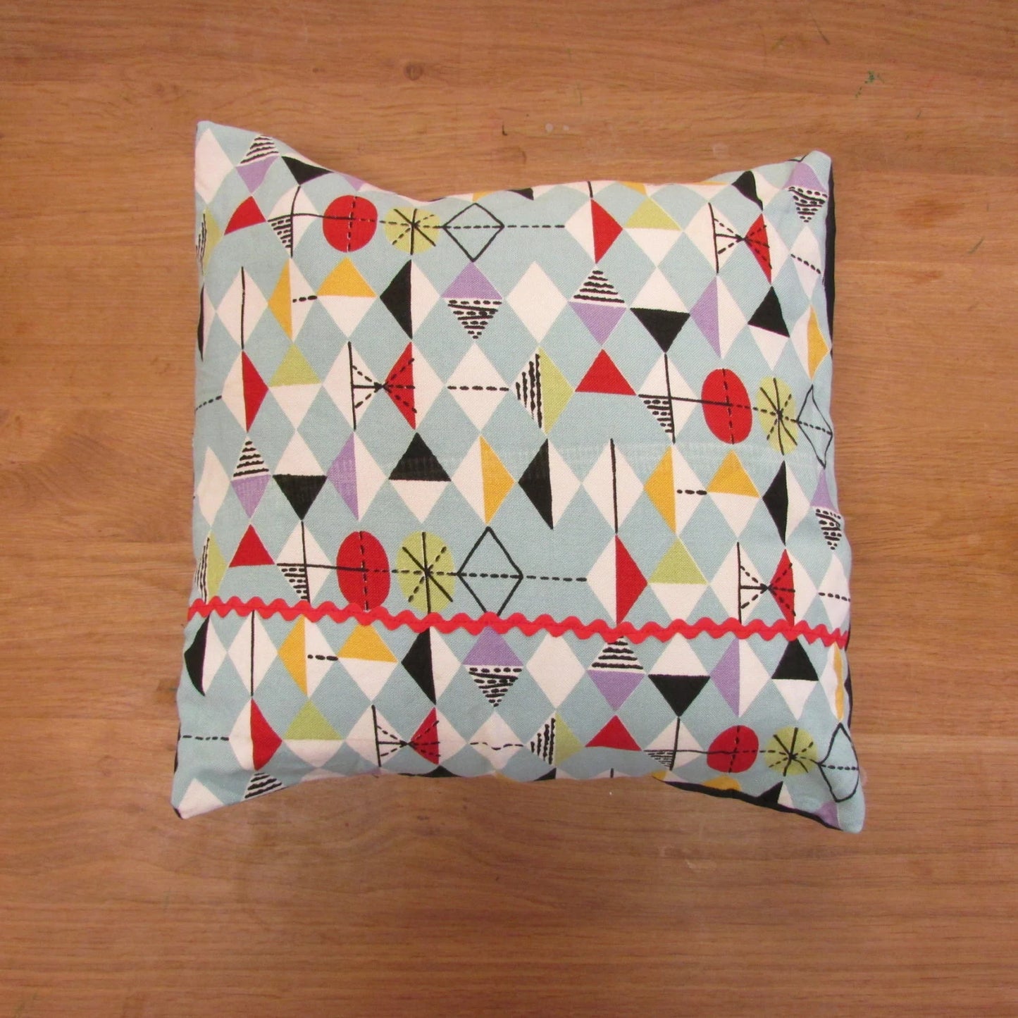 Home-made mid-century Marian Mahler atomic fabric cushion with red ric-rac, and contrast black reverse