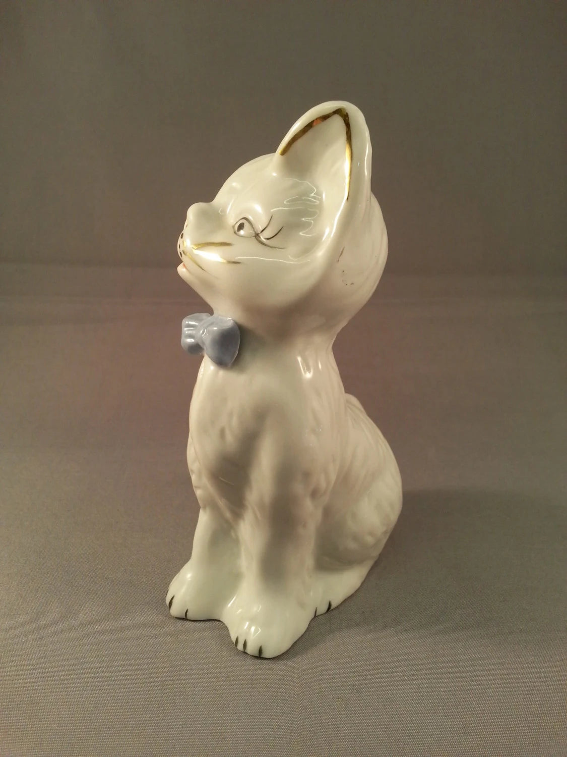 circa. 1960s kitsch white kitten ornament with blue bow